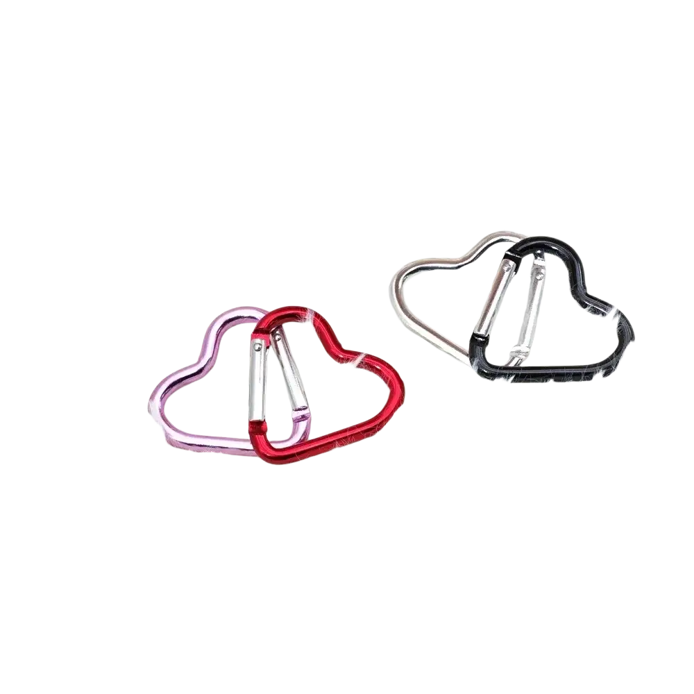 Heart shaped carabiner keychain set with pink red and black metallic finishes on a white fluffy surface