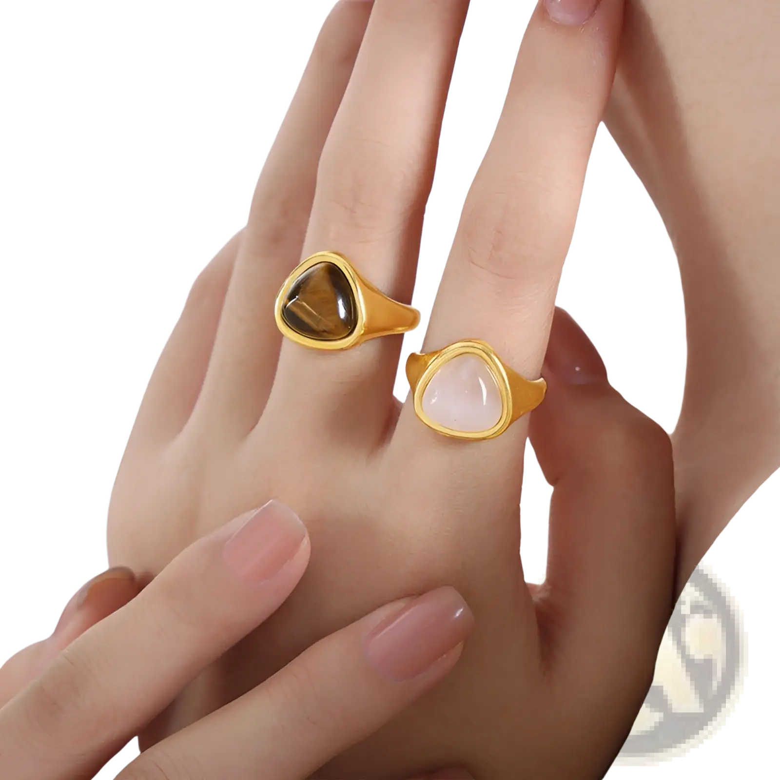 Two gold-toned titanium steel signet rings featuring a triangular tiger’s eye and a pink moonstone heart-shaped stone