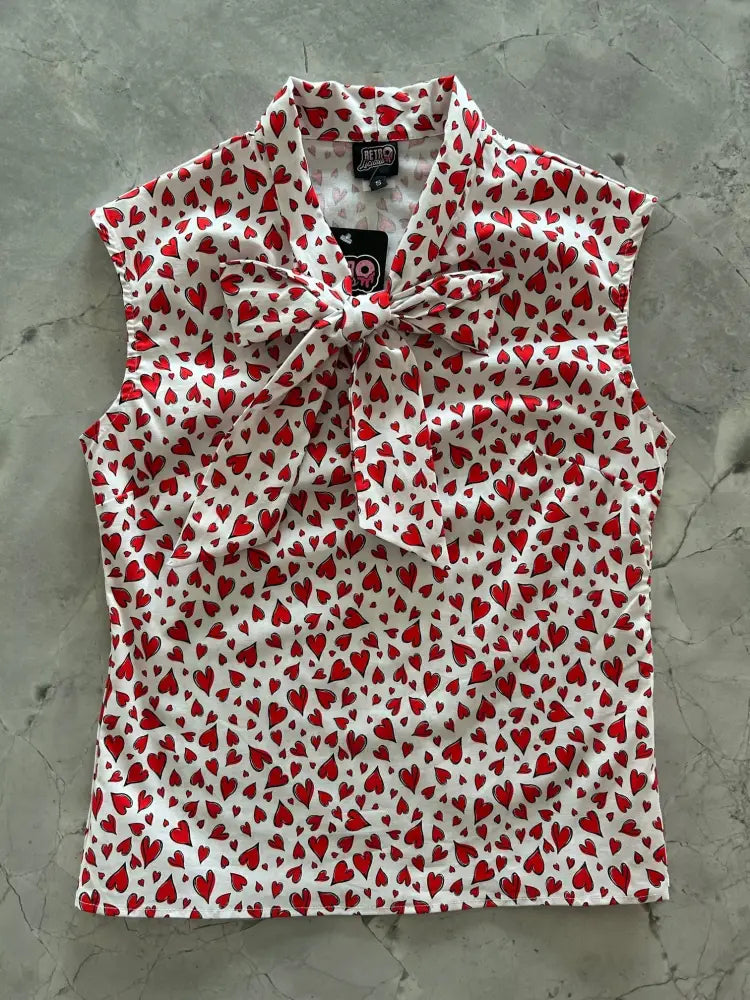 Vintage 1950s white sleeveless blouse with red heart print and tied bow at the neckline for stylish wear