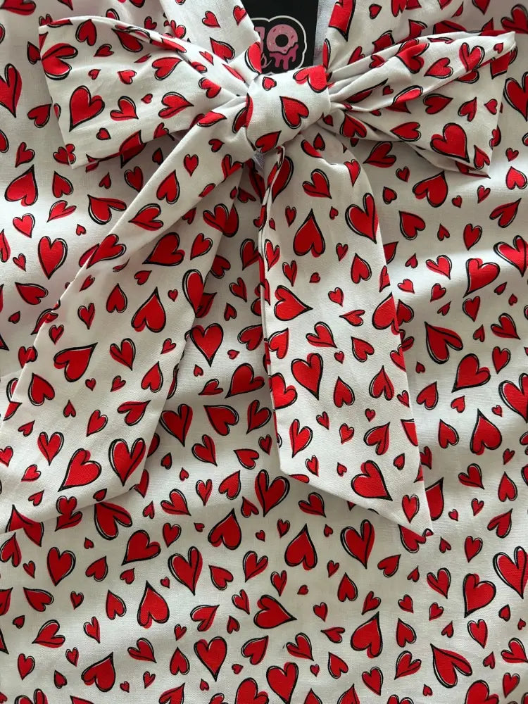Vintage 1950s white sleeveless fabric top with red heart print and tied neckline bow
