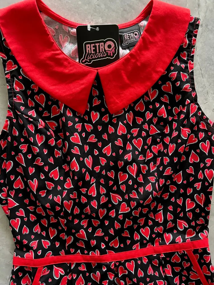 A black cotton sleeveless dress with vibrant red heart pattern and plush red peter pan collar retro style