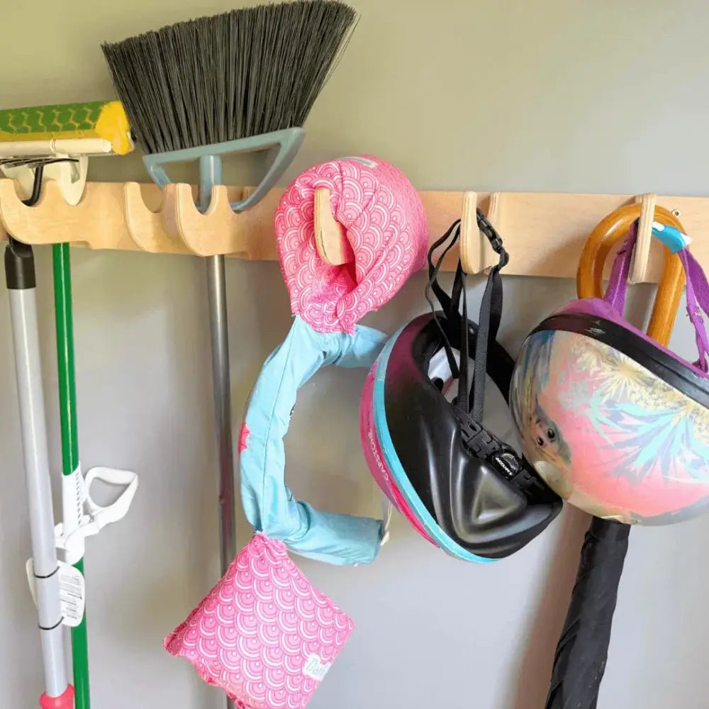 Pink patterned helmet cover with scalloped design hanging on birch plywood heavy duty garage wall tool rack