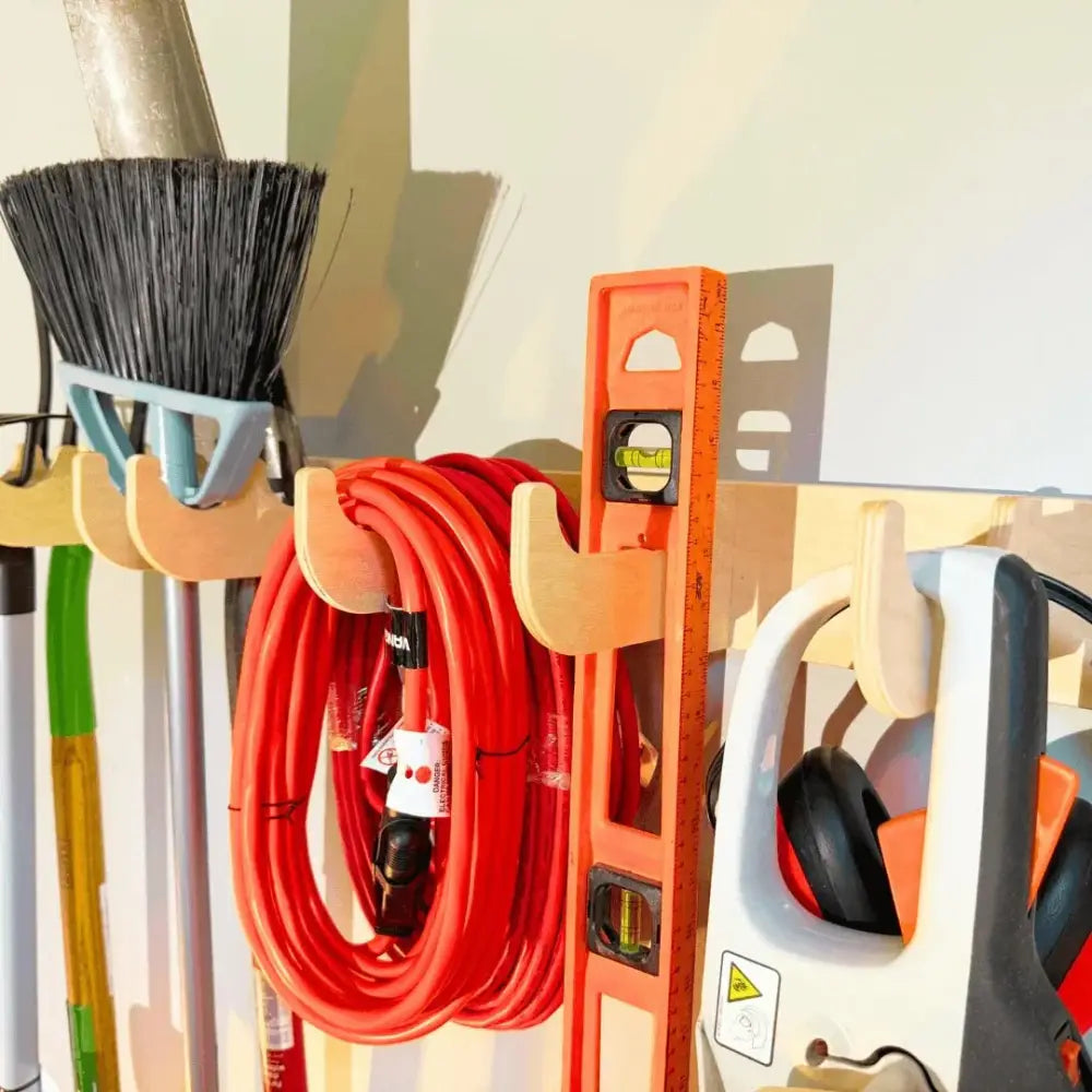 Orange spirit level with black liquid vial and white markings on birch plywood heavy duty garage wall tool rack