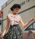 A woman wears a sleeveless vintage hedgeghog print cotton bow blouse with a white base and black butterfly print
