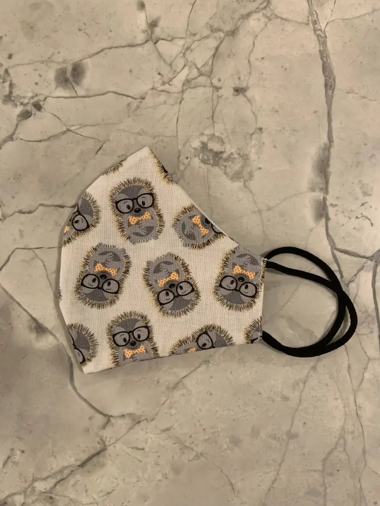 Reversible hedgehog print cotton face mask with white fabric featuring gray hedgehogs wearing glasses and bow ties