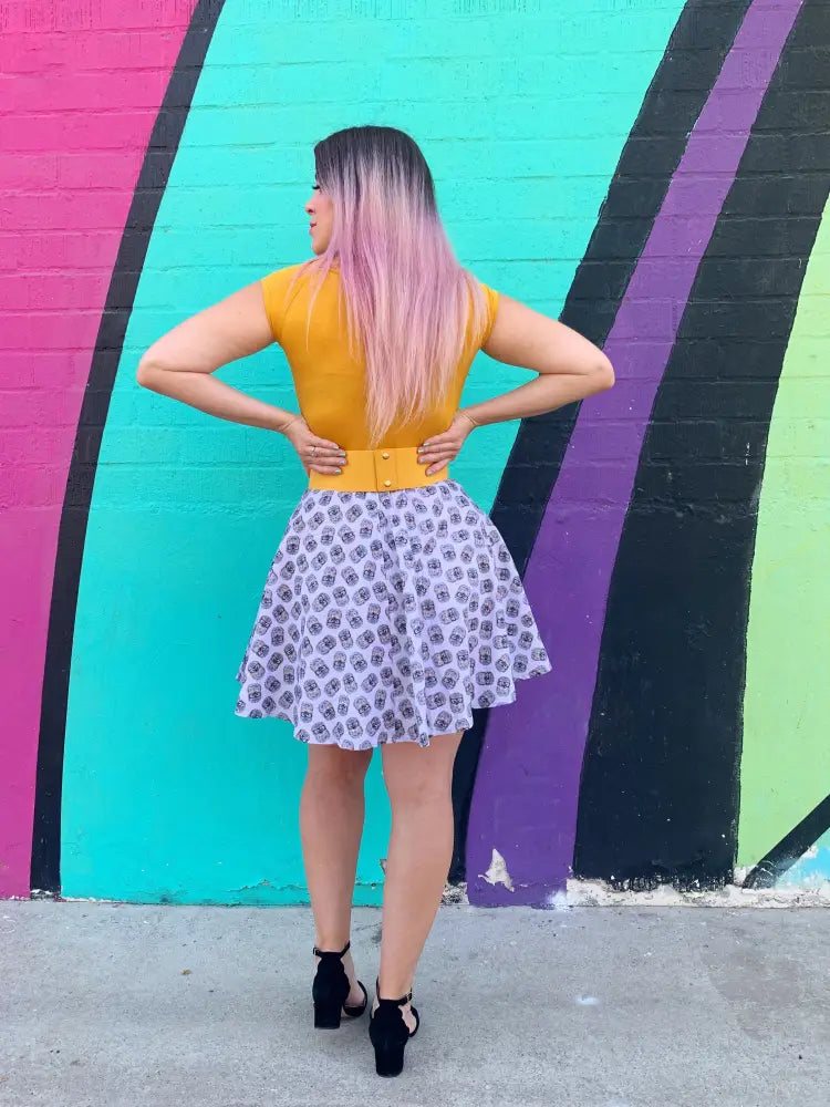 A woman wearing a retro hedgehog print cotton skater skirt with a subtle purple geometric pattern and a yellow sleeveless top
