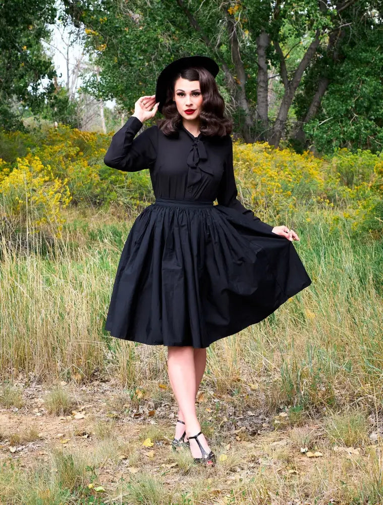 Black vintage-style dress with fitted bodice bow at neckline and full skirt ideal for formal occasions
