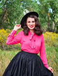 Vibrant pink long sleeve blouse with a bow tie neckline made of lightweight fabric for retro style