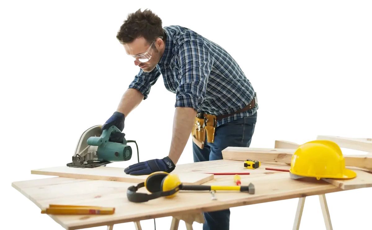 A man wearing high dexterity blue touch screen work gloves uses a green circular saw on a wooden workbench
