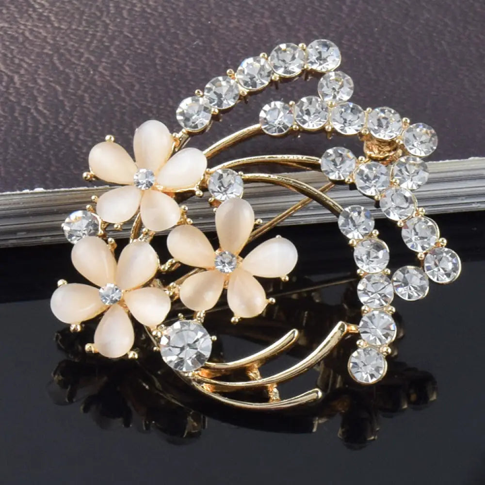 Vintage opal and rose gold floral bridal brooch with three pale peach flowers and a curved rhinestone arch