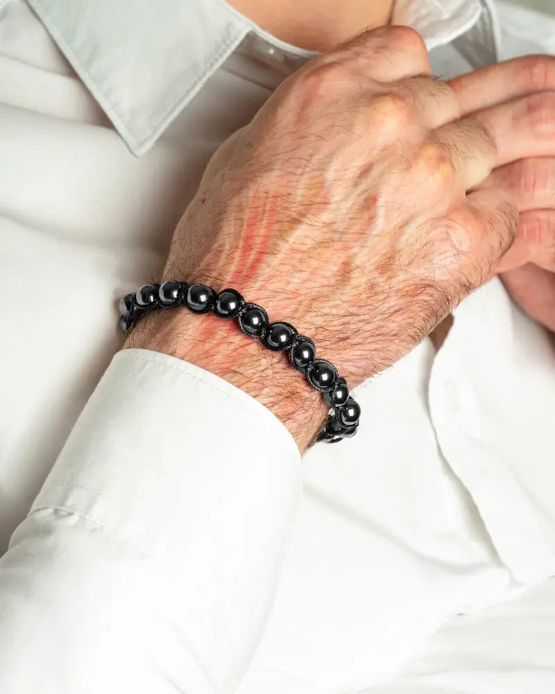 Black beaded bracelet with magnetic hematite beads worn on a man’s wrist for high power energy benefits