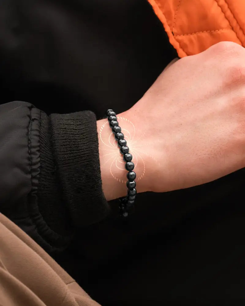 Black beaded high power 6mm magnetic hematite bracelet with steel charm worn on a wrist showing front side