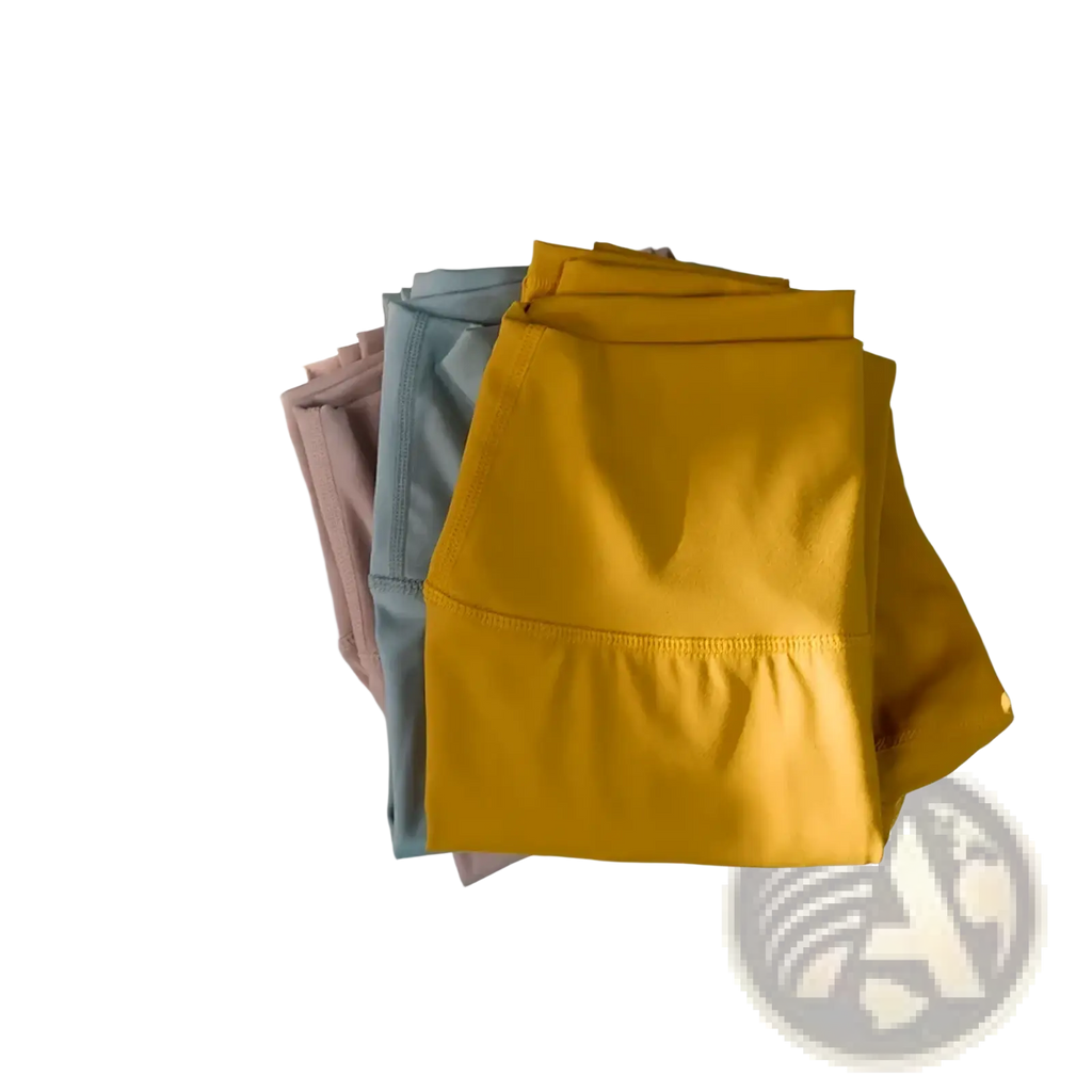 A stack of neatly folded high-waisted yoga leggings for women in mustard yellow dusty rose and soft gray for activewear