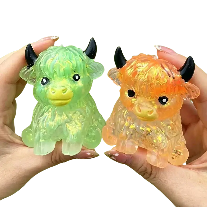 Two translucent glitter-filled resin highland cow sensory fidget toys in green and orange for stress relief