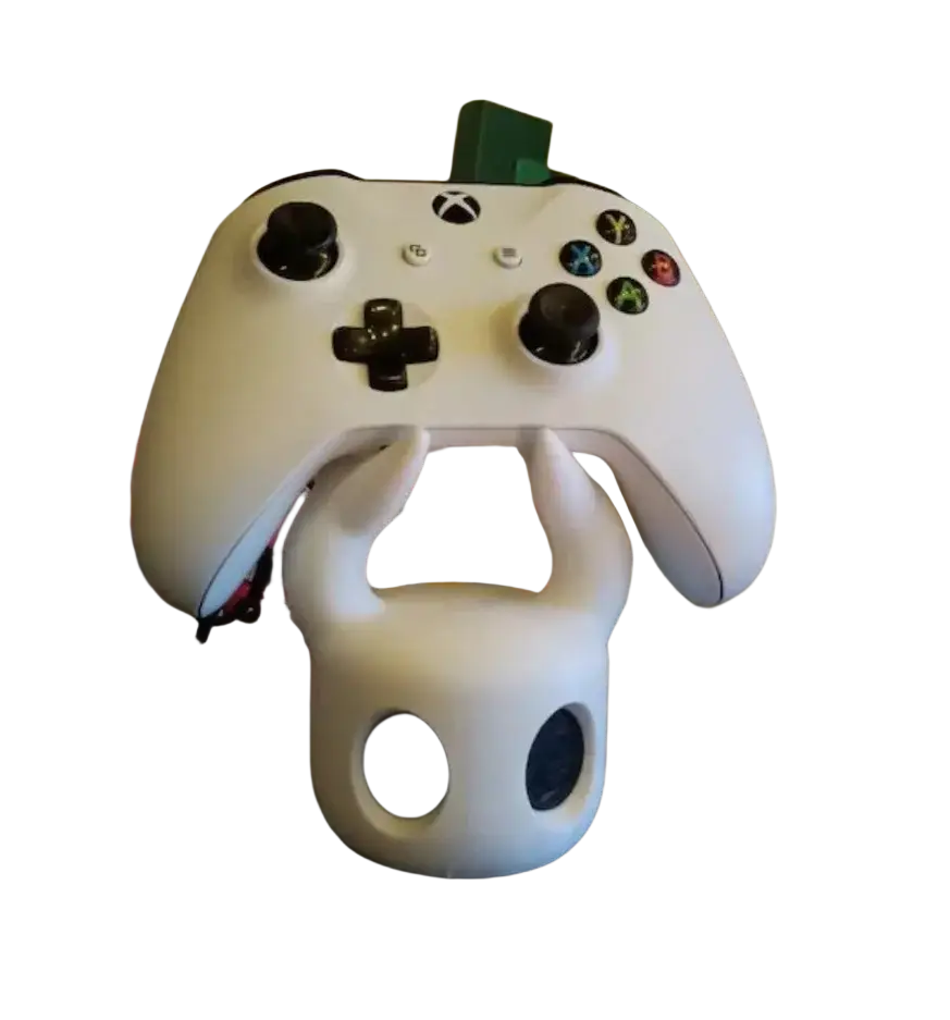 White xbox controller resting on white horned skull-shaped hollow knight game controller stand for ps5 display