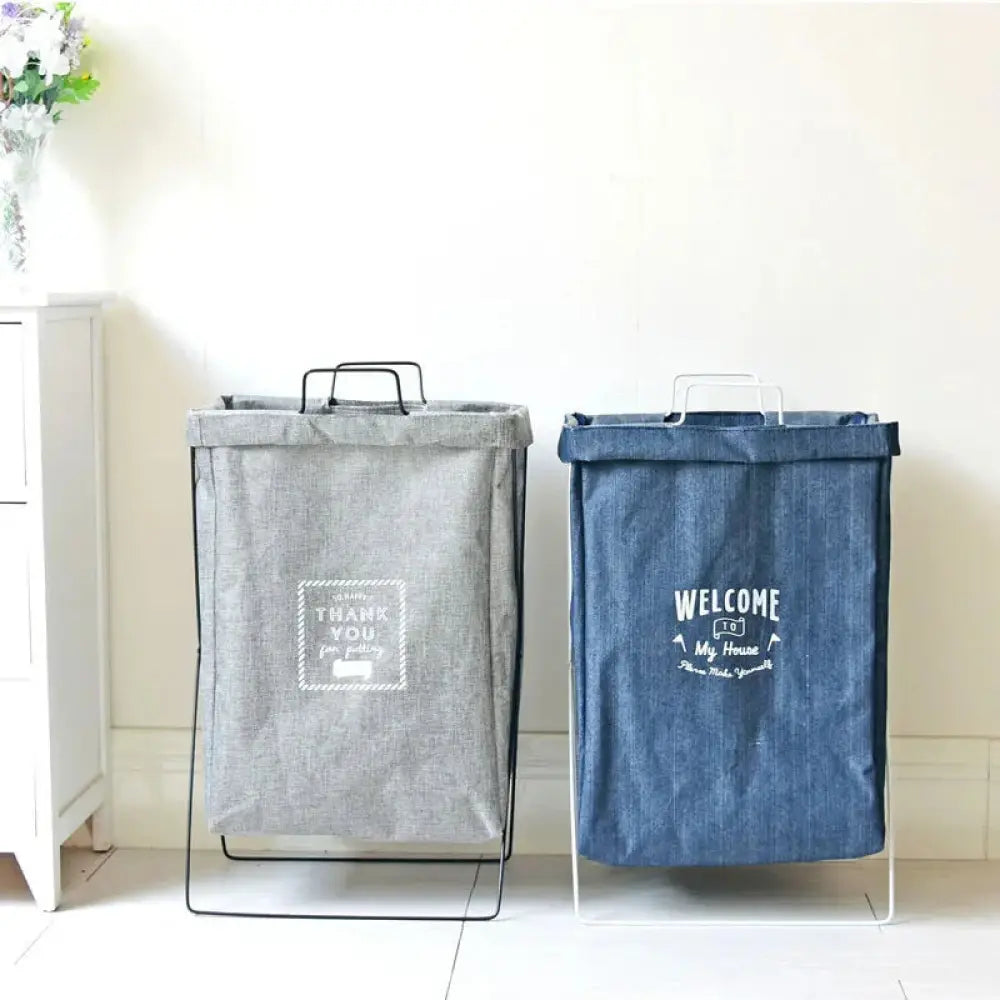 Gray and blue embroidered denim laundry baskets with white metal frames and embroidered text for fabric storage