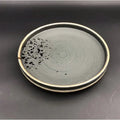 Minimalist Japanese ceramic speckled tableware set featuring a sleek dark gray plate with concentric rings and beige rim