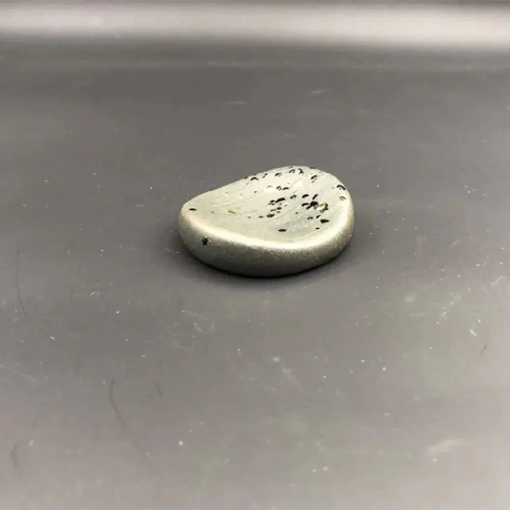 A teardrop-shaped silver-toned ceramic plate with black speckles from a minimalist japanese speckled tableware set