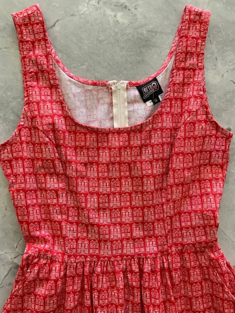 A red cotton fit and flare dress with white building print square neckline and back zipper closure shown from the back