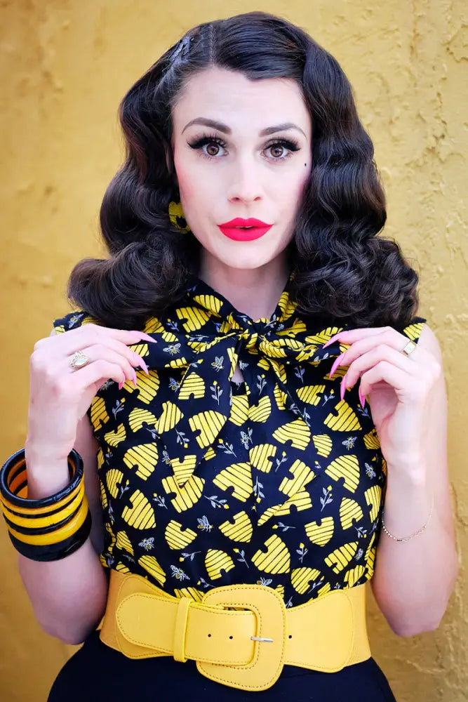 Yellow leather belt with prominent rectangular buckle paired with honey hives vintage 1950s cotton bow top