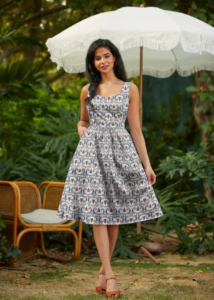A woman wearing a sleeveless Honey Im Home retro fit and flare cotton dress with a white and navy blue geometric pattern