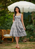 A woman wearing a sleeveless Honey Im Home retro fit and flare cotton dress with a white and navy blue geometric pattern