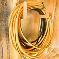 Heavy duty wall mounted hose and extension cord organizer holding a coiled yellow and black Stanley Fatmax air hose