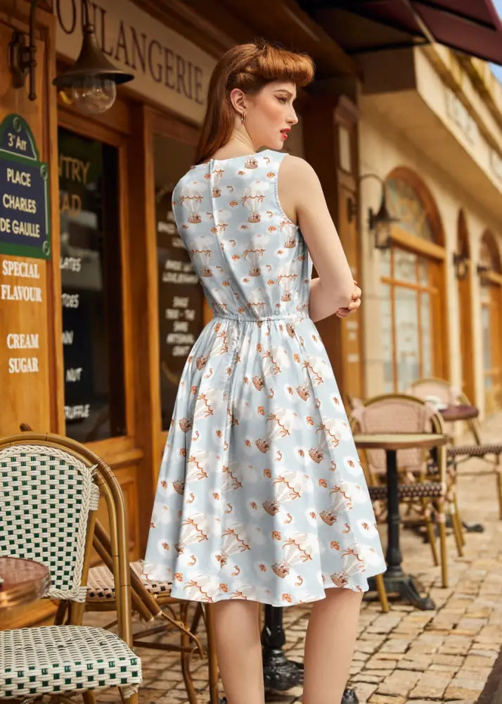 A light blue sleeveless vintage hot air balloon cotton a-line dress with a playful pattern of small brown flamingos