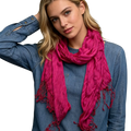 A vibrant hot pink crinkle scarf with soft textured fabric and frayed edges for stylish women accessory