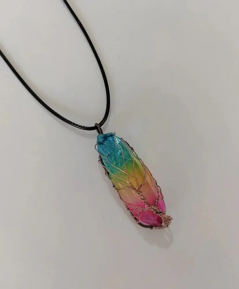 A vibrant rainbow-colored wire-wrapped crystal pillar pendant necklace hanging from a black cord