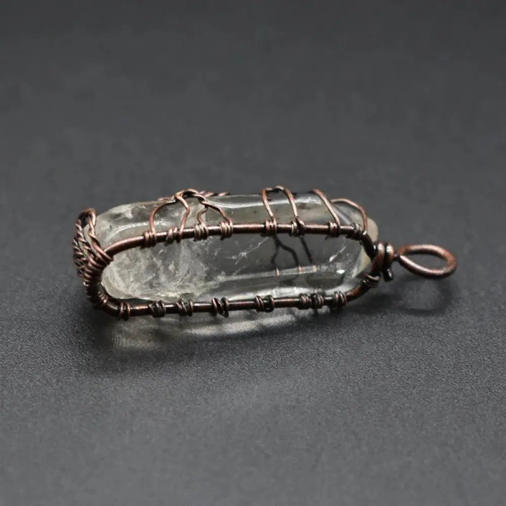 A clear quartz crystal pendant encased in hand-wired copper with a loop for hanging rainbow tree of life necklace
