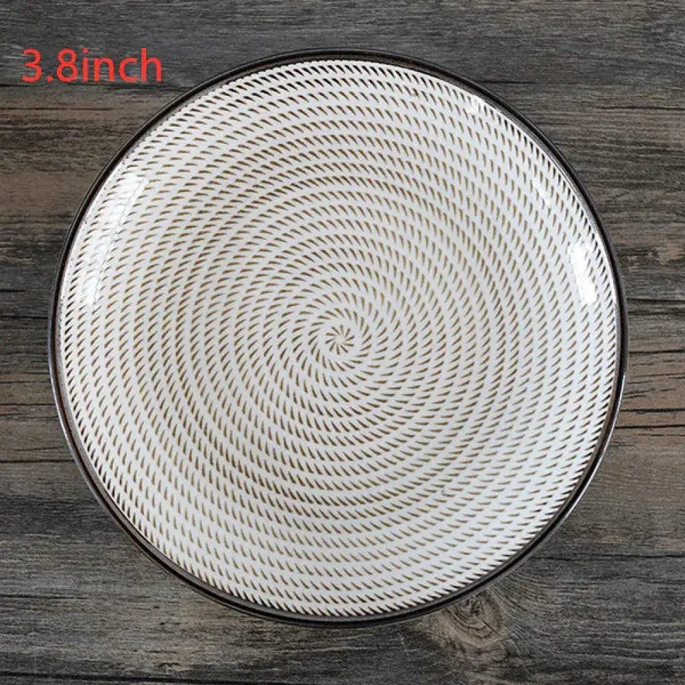 A minimalist Japanese white ceramic plate with a black rim and dark gray spiral patterns for dining use