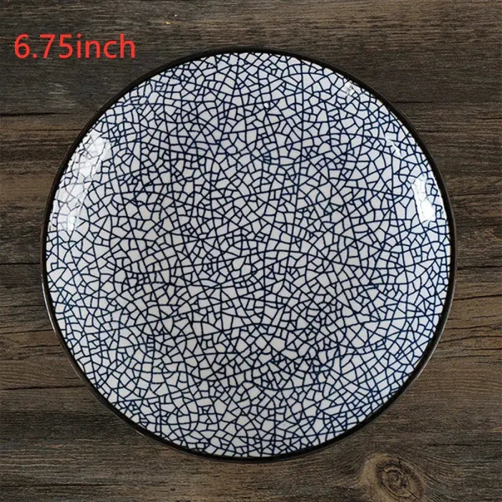 A minimalist white ceramic plate with black crackle glaze pattern and dark rim measuring 6.75 inches in diameter