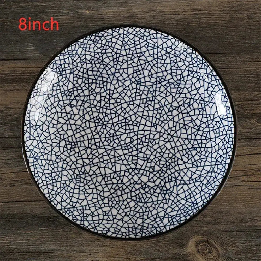 An 8-inch round white glazed ceramic plate with black crackle pattern and dark rim from minimalist Japanese tableware