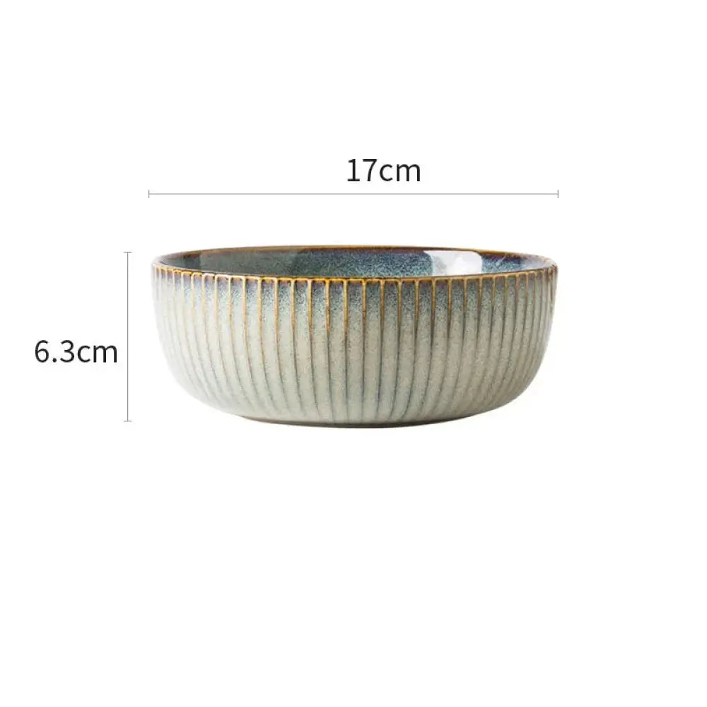 A ceramic bowl from a nordic dinnerware set with vertical ridges and a gradient glaze from gray to deep blue