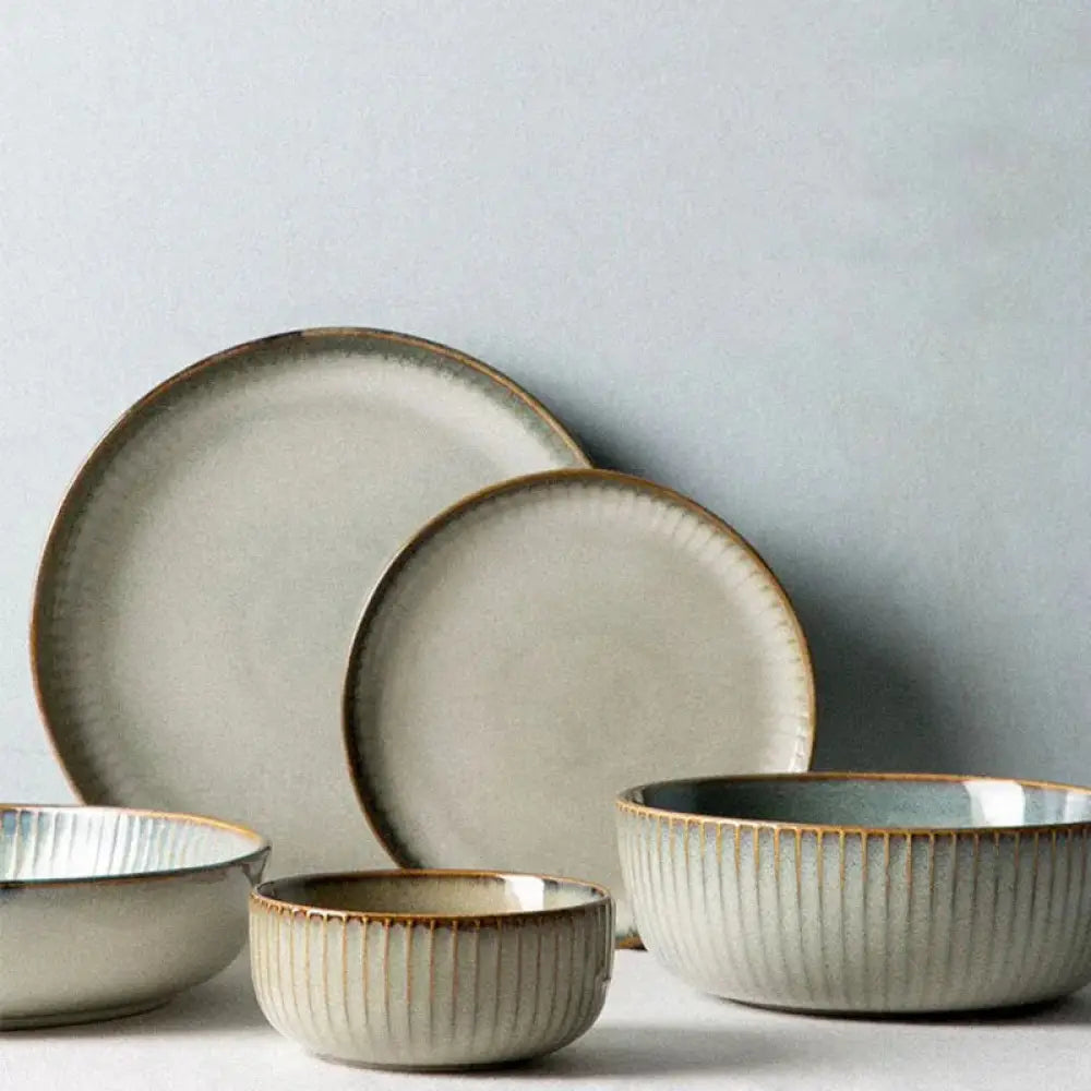 Nordic ceramic dinnerware set featuring matte gray glaze, subtle brown rims, and vertical ridges on minimalist bowls