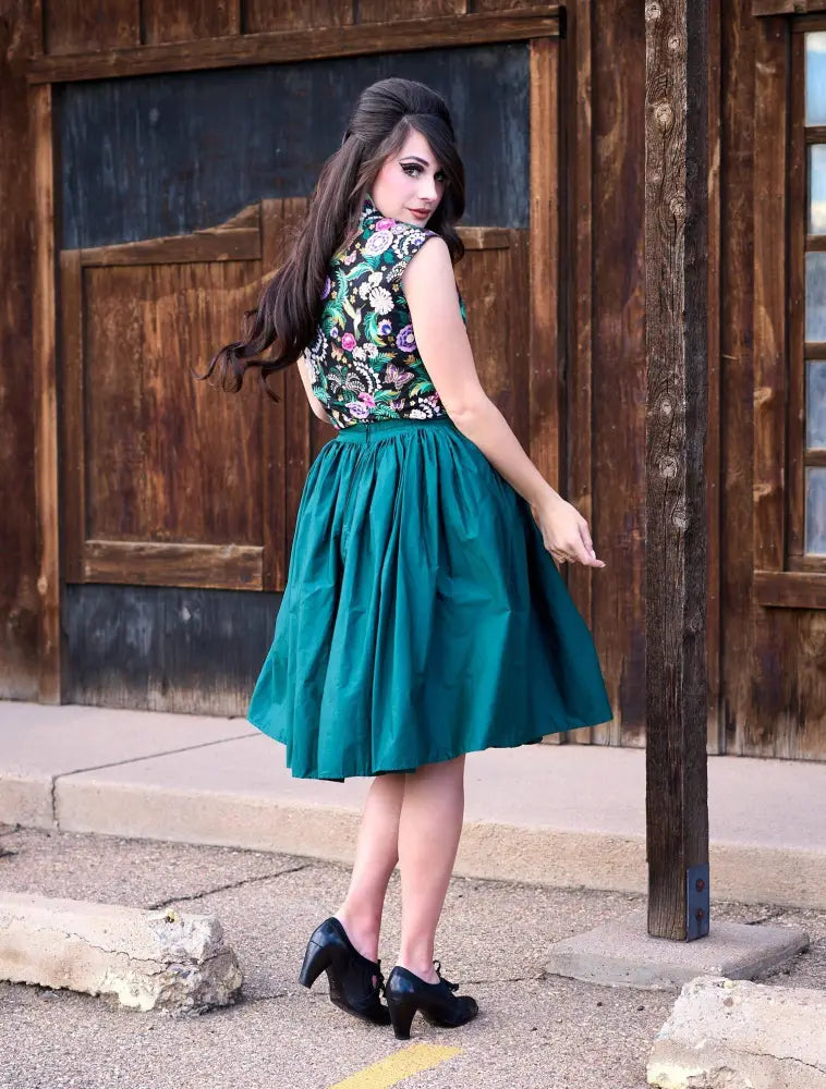A woman wears a hummingbird print vintage bow top 100 percent cotton blouse with green purple and white embroidery