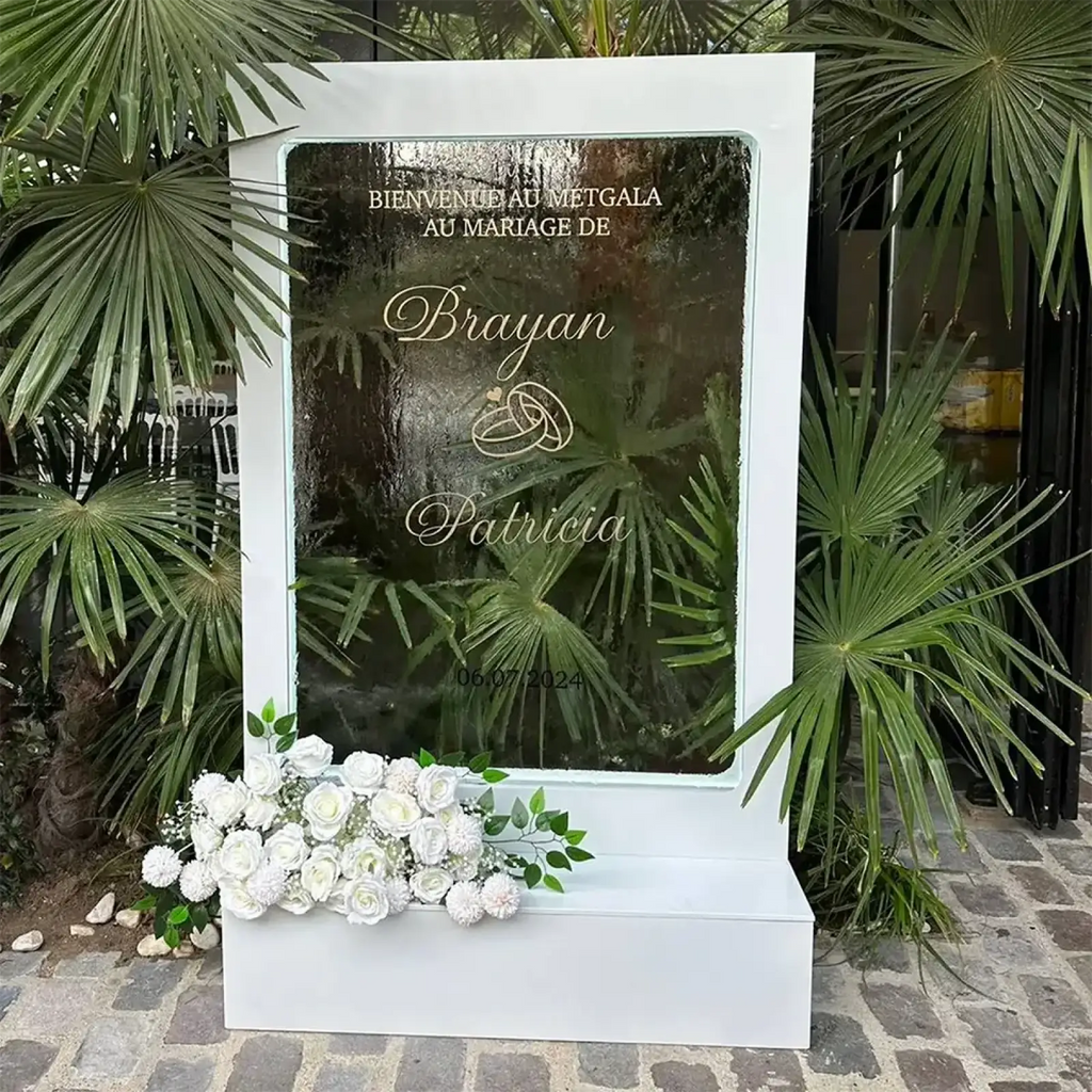White rectangular wedding welcome sign with frosted glass panel gold-etched text and floral base for illuminated backdrop