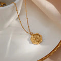 A gold-toned engraved floral pendant necklace with a hexagonal textured design named in the garden