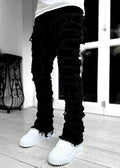 Men’s slim fit stacked ripped patchwork streetwear jeans in black distressed denim with frayed ripped detailing along legs