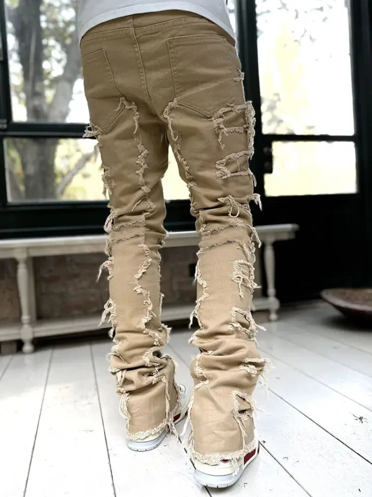 Men’s slim fit tan distressed denim jeans with frayed ripped detailing for streetwear style and stacked patchwork design