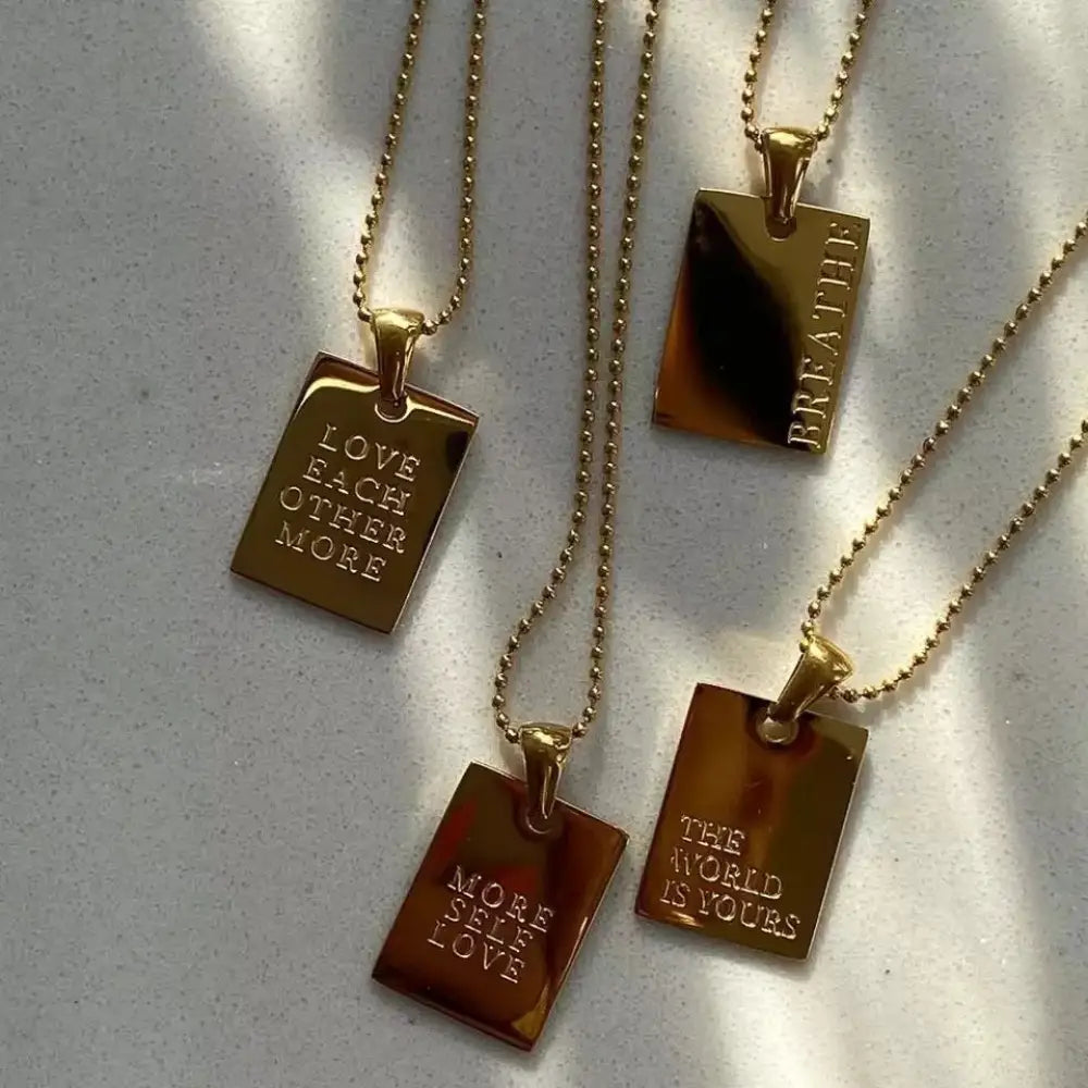 Gold layered breathe engraved tag necklaces with gold-toned rectangular pendants and delicate ball chains