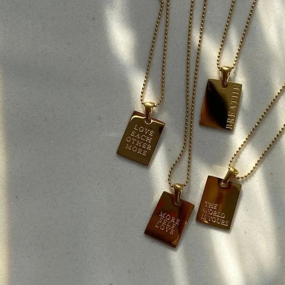 Gold-toned rectangular pendant necklaces with engraved inspirational phrases from the gold layered breathe tag collection