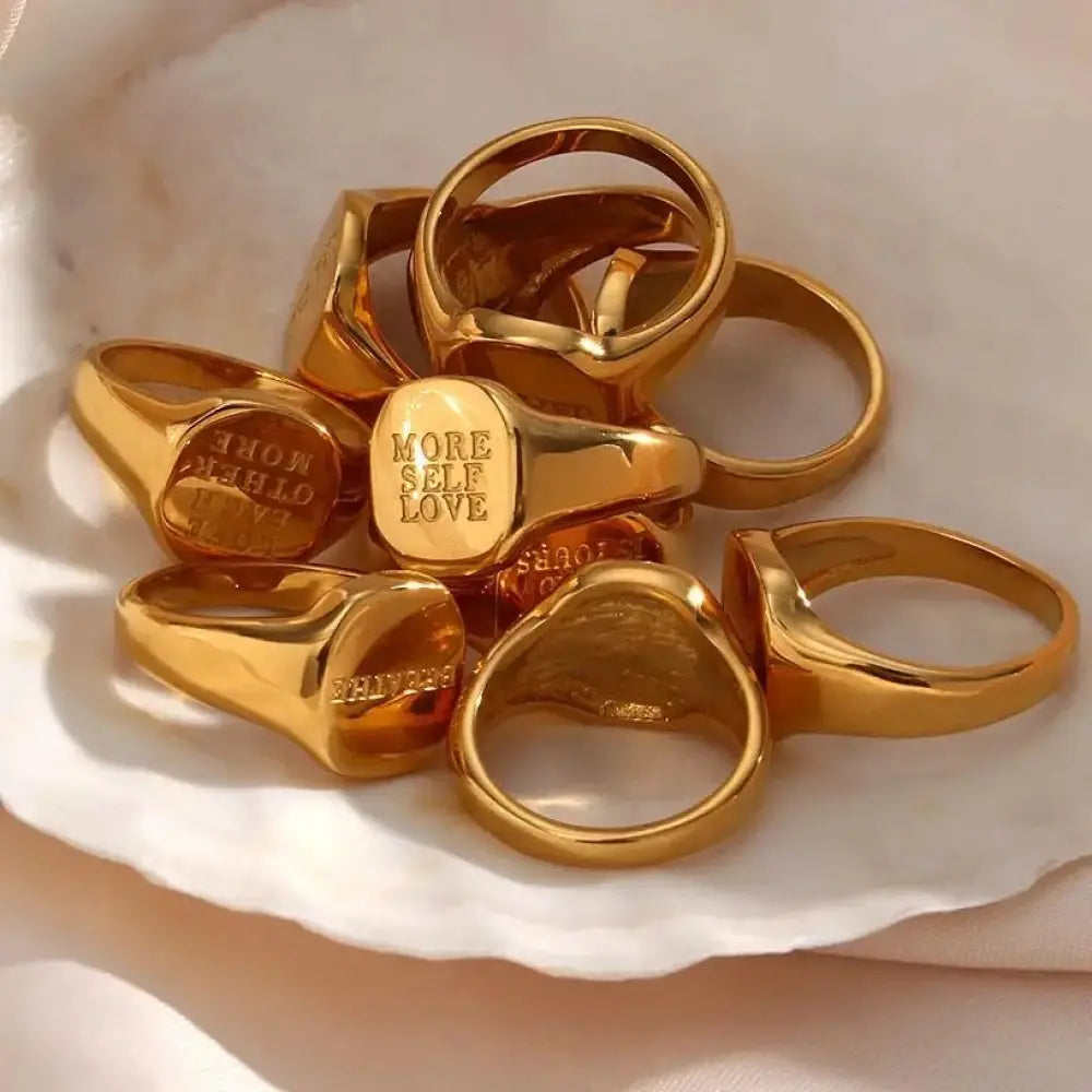 Engravable gold toned signet rings with motivational phrases and a polished metallic finish for inspiration