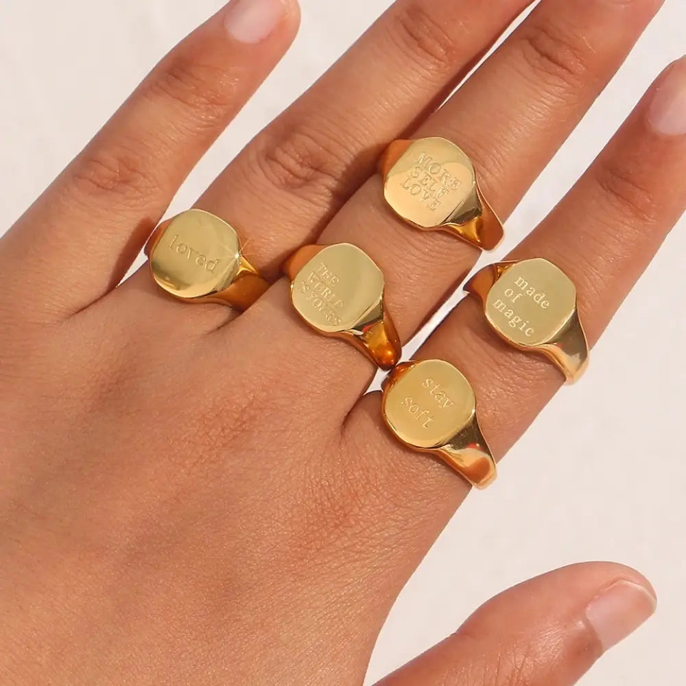 Gold toned engraved inspirational signet rings with phrases loved made of magic and star soft on a hand