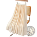 A flowing cream-colored iridescent chiffon pleated skirt made of lightweight fabric hanging on a wooden hanger