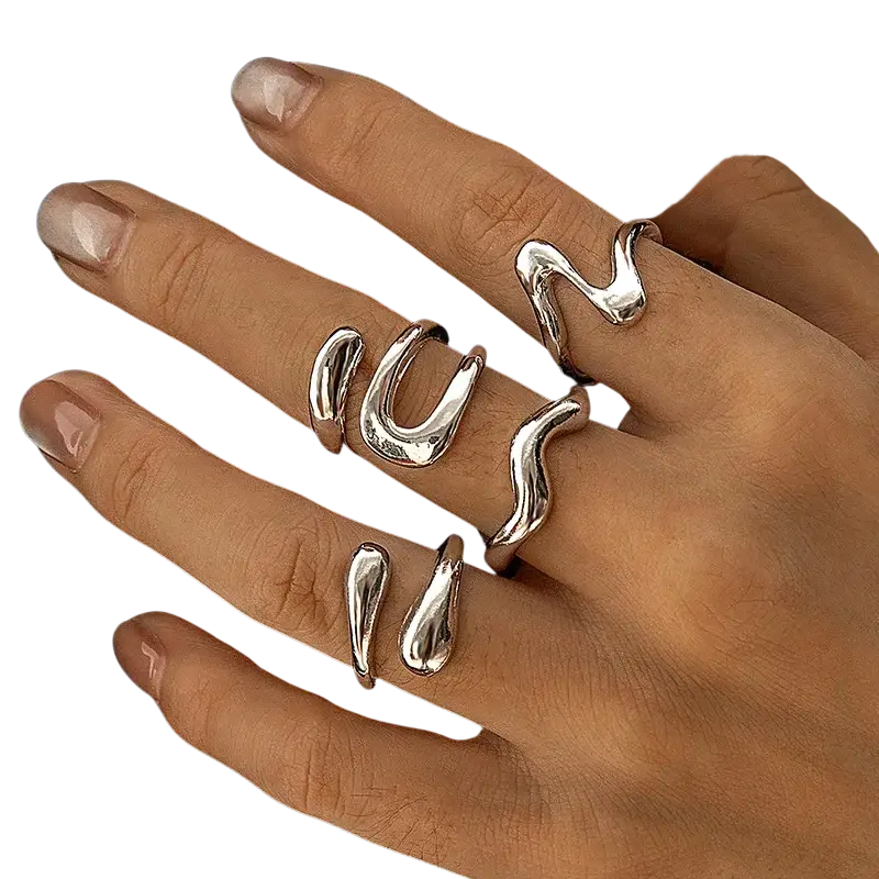 A set of five silver irregular geometric rings with fluid wavy and teardrop shapes worn on fingers for fashion
