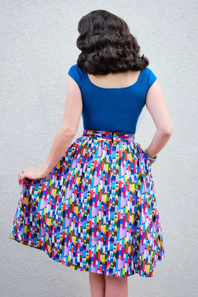 A vibrant a-line skirt with a bold multicolored geometric pattern paired with an Isabel sweetheart ruched top in peacock blue jersey