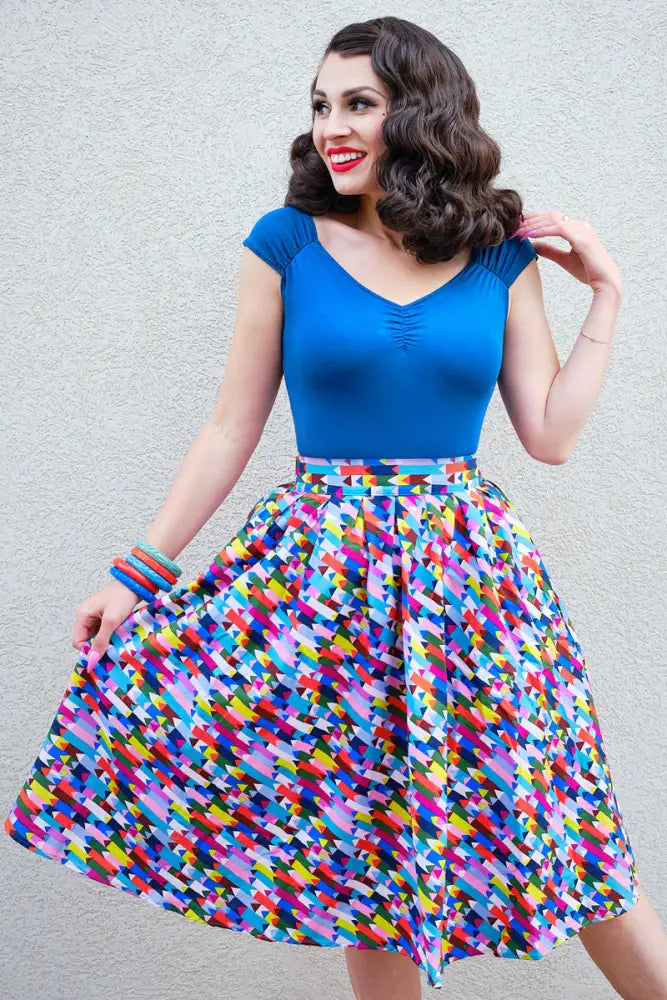 Vibrant multicolored geometric patterned a-line skirt with high waist and flared hem paired with peacock blue jersey ruched top