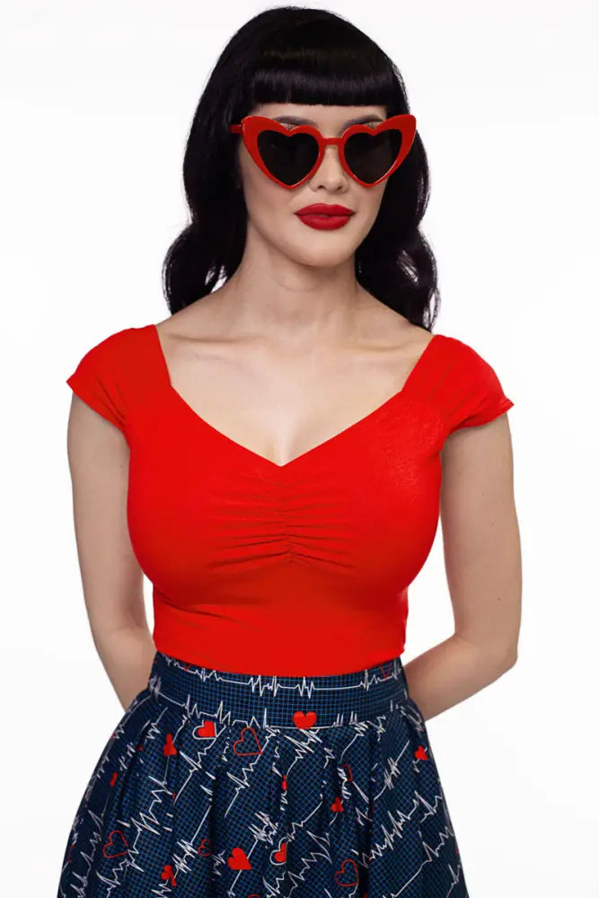 Isabel red sweetheart retro knit top paired with red heart-shaped sunglasses with black lenses
